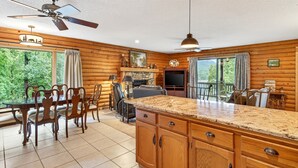 A log cabin interior with a dining area, kitchen, and a balcony with a view of the outdoors. - Pet Friendly, Views, Lake Lure Access, Wi Fi - My Mountain Paradise (Lake Lure)