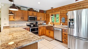 A modern kitchen with wooden cabinets, granite countertops, stainless steel appliances, and a view of greenery outside. - Pet Friendly, Views, Lake Lure Access, Wi Fi - My Mountain Paradise (Lake Lure)