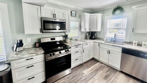 Una cocina moderna con armarios blancos, estufa de acero inoxidable, microondas y cafetera.