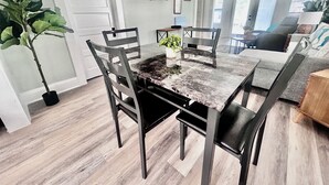 Un comedor con una mesa de mármol, sillas oscuras y una planta en maceta.