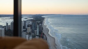 Une vue sur un paysage urbain côtier, avec de hauts immeubles le long de la plage, prise depuis une fenêtre.
