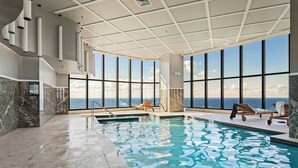 An indoor swimming pool with clear views of the ocean through large windows.