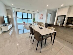 Een moderne keuken met een groot kookeiland, een eethoek met een marmeren tafel en uitzicht op de oceaan.