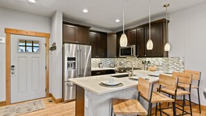 Una cocina moderna con armarios de madera oscura, electrodomésticos de acero inoxidable y una isla central con taburetes de bar.