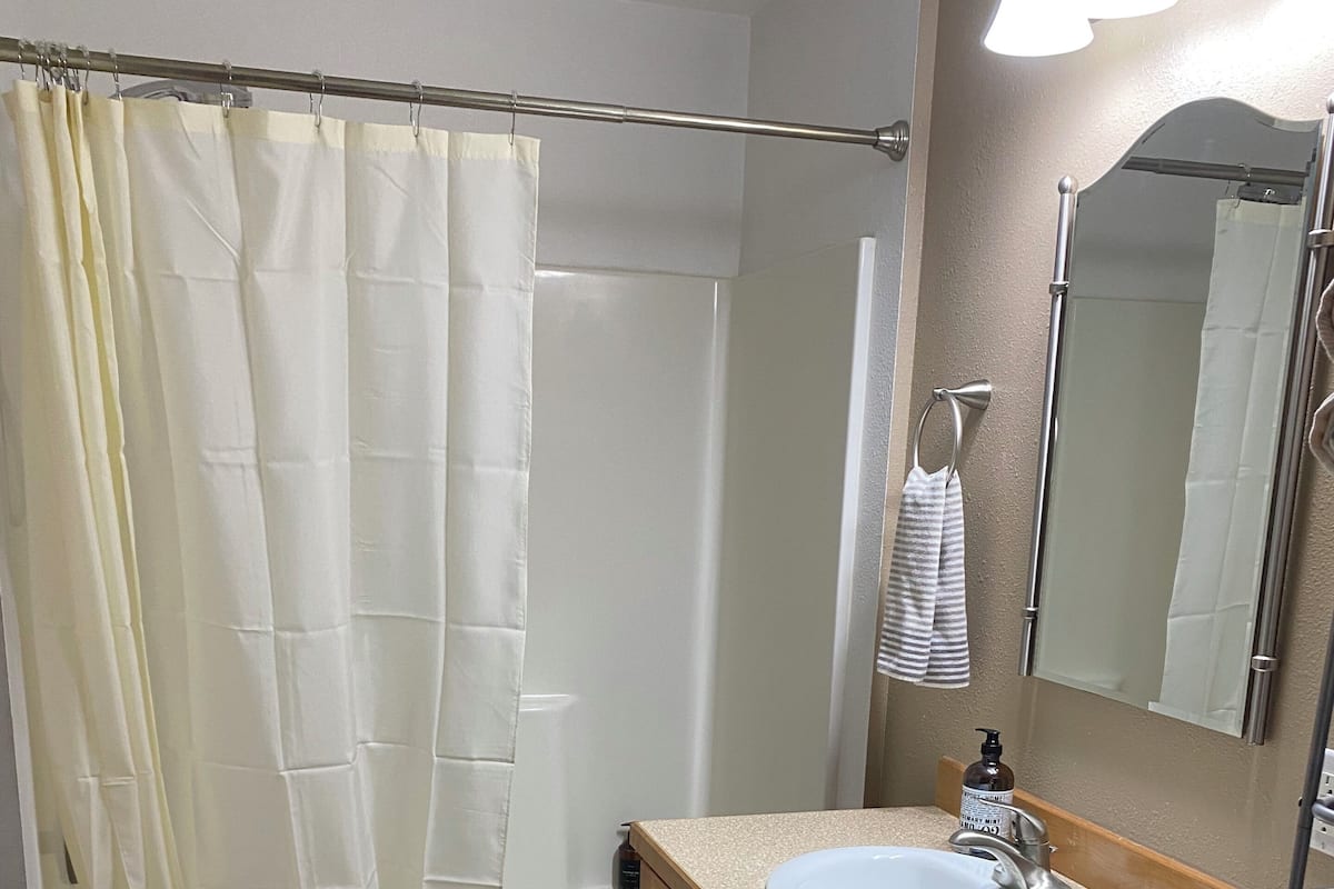 A bathroom with a bathtub, a sink, a mirror, and a shower curtain.