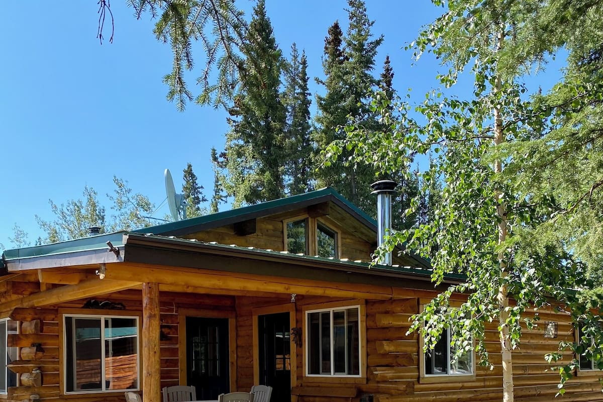 A log cabin with a porch, a table, and chairs.