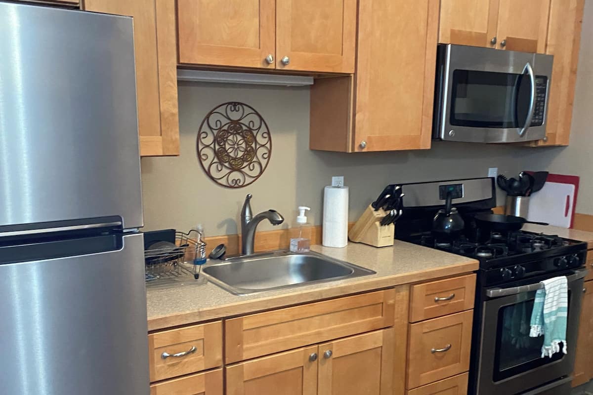 A kitchen with wooden cabinets, stainless steel appliances, a sink, and a decorative wall piece.