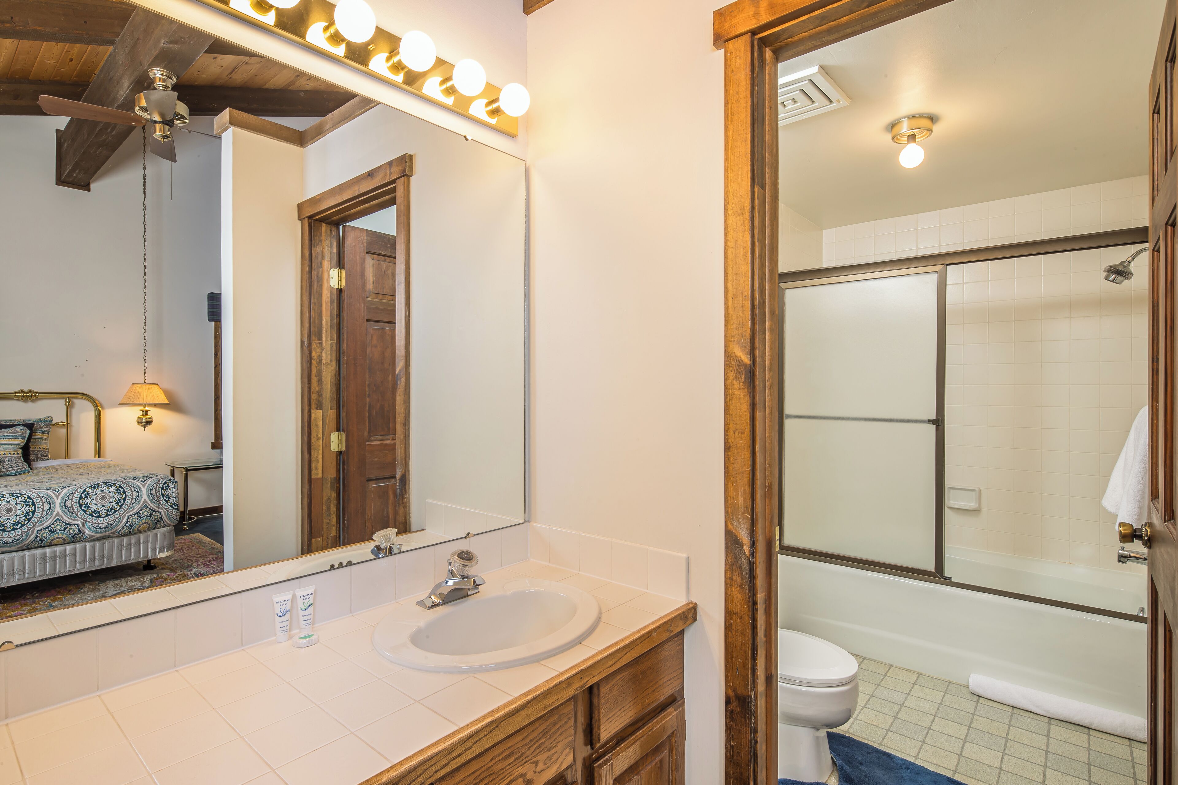 A bathroom with a vanity, sink, mirror, and a shower area.