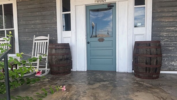 A wooden porch with a blue door, numbered 20601, and two barrels. - 1800 Historic Studio in  downtown Dunnellon Rainbow River World Equestrian ctr (Dunnellon)