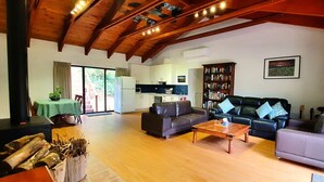 A spacious living area with a wooden ceiling, a fireplace, a sofa, a coffee table, and a bookshelf.
