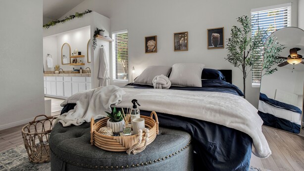 A bedroom with a bed, bedside table, and a large mirror. - Azure Oasis - Saltwater Pool/Spa with putting green! (Palm Desert)