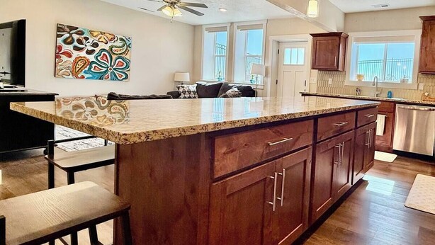 A spacious kitchen with a large island, wooden cabinets, and pendant lighting.