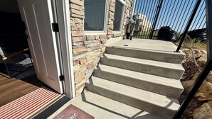 A set of concrete steps leading to a door with a 'Welcome Home' mat.
