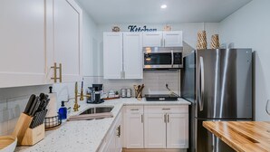 A modern kitchen with white cabinets, stainless steel appliances, and a wooden countertop. - Charming studio in tranquil Naples with AC. (Naples)
