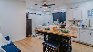 A modern kitchen with a wooden countertop, bar stools, and white cabinets. - Charming studio in tranquil Naples with AC. (Naples)