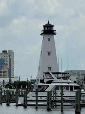 A white lighthouse with a black top, situated next to a dock with a boat.