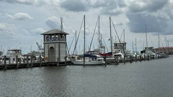 A marina with multiple boats docked, a small tower structure, and a cloudy sky.