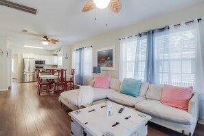 A living room with a sectional sofa, a coffee table, and a dining area with chairs and a table.