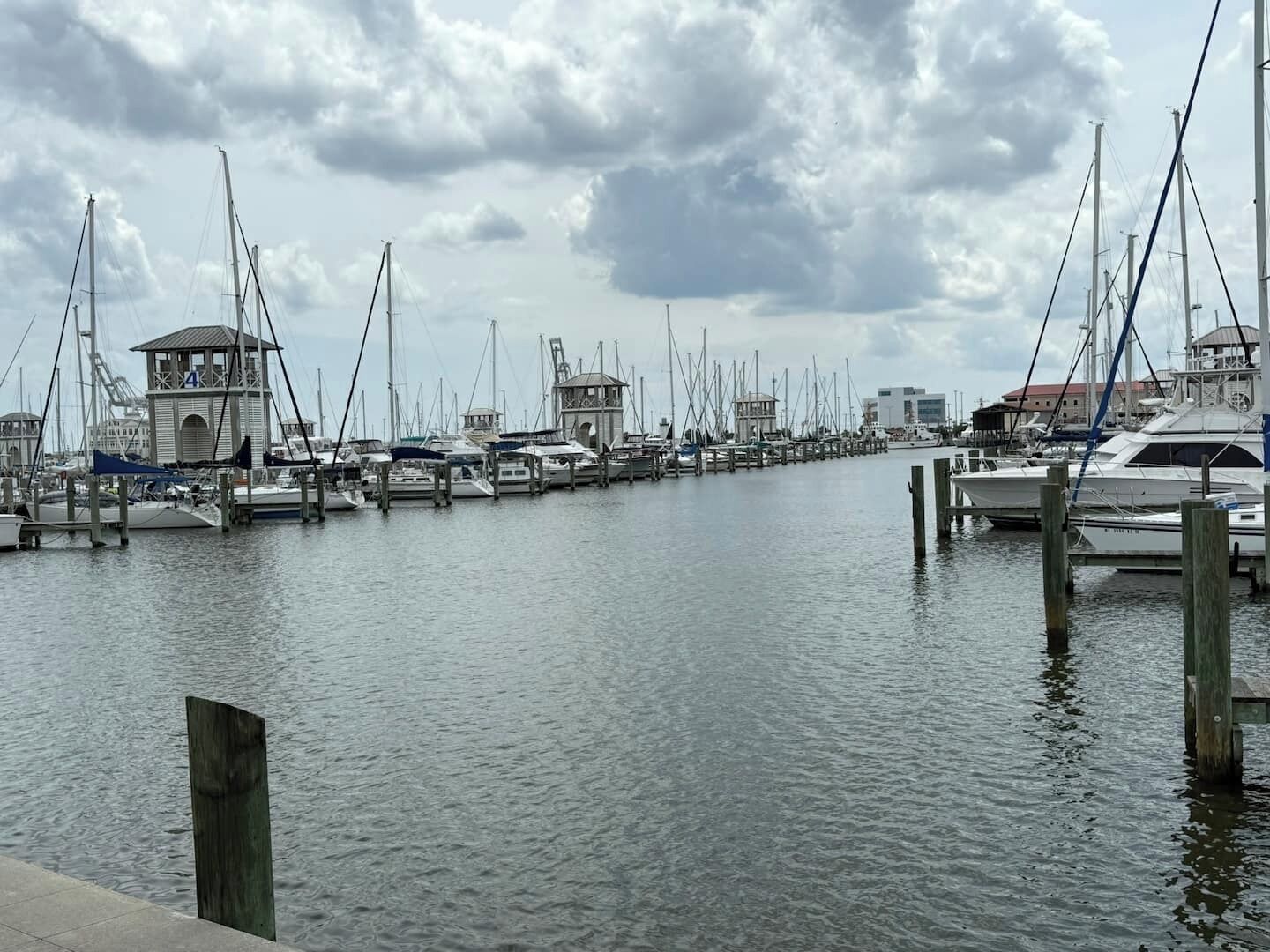 Un port de plaisance où sont amarrés de nombreux bateaux, une petite structure en forme de tour et une étendue d’eau calme.