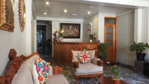 Eine großzügige Lobby mit einer Couch, Sesseln und einem Holzbüro.
