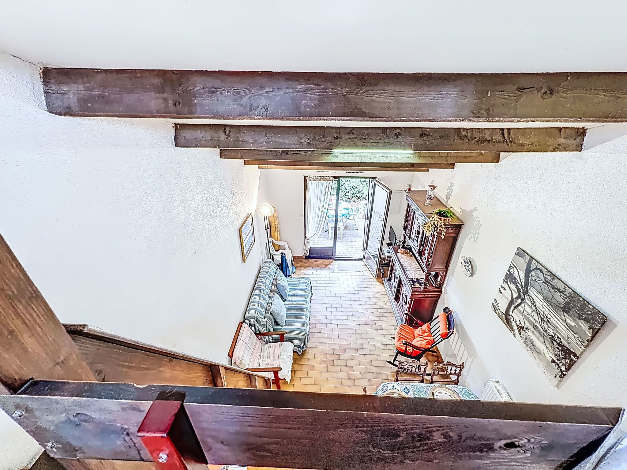 A spacious hallway with a tiled floor leading to a balcony with a view of the outdoors.