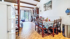 A dining area with a wooden table set for four, surrounded by chairs. A large cabinet with decorative items is visible in the background. - Les Maisons de la Plage by Interhome (Le Grau du Roi)