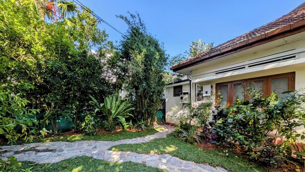 A garden pathway leading to a house with a tiled roof and a small porch area. - Nomads Hideaway Near Matara Railway Station (Matara)