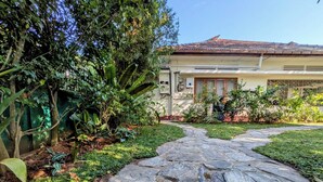 A stone pathway leading to a house with a tiled roof, surrounded by lush greenery and various plants. - Nomads Hideaway Near Matara Railway Station (Matara)