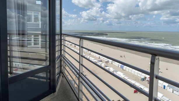 A balcony with a view of the beach and ocean.