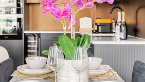 Une cuisine moderne avec des meubles en bois, un plan de travail blanc et un vase rempli de fleurs roses.