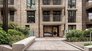 Un bâtiment moderne avec une façade en briques, de nombreux balcons et une entrée centrale.