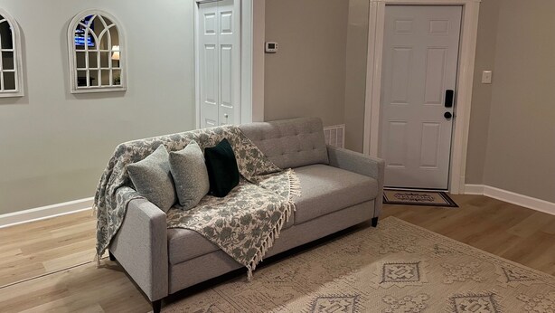 A living room with a grey sofa, patterned throw, and a patterned rug.