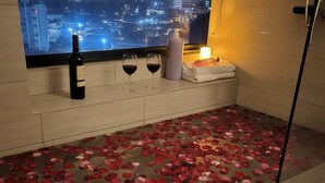 Ein Zimmer mit Blick auf die Stadt, eine Weinflasche, zwei Weingläser und ein Handtuch auf einem Regal.