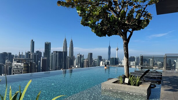 Ein Infinity-Pool auf dem Dach mit Blick auf die Stadtlandschaft, darunter die Petronas Towers.