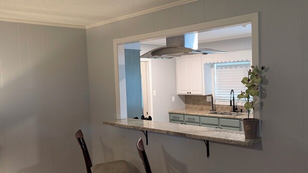 A room with a kitchen area visible through a window, two chairs, and a wooden floor. - Forget your worries in this spacious and serene space. (Monroe)