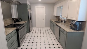 A compact kitchen with a central island, a built-in oven, and a coffee maker. - Forget your worries in this spacious and serene space. (Monroe)