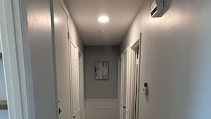 A hallway with wooden flooring, white walls, and doors on both sides. - Forget your worries in this spacious and serene space. (Monroe)