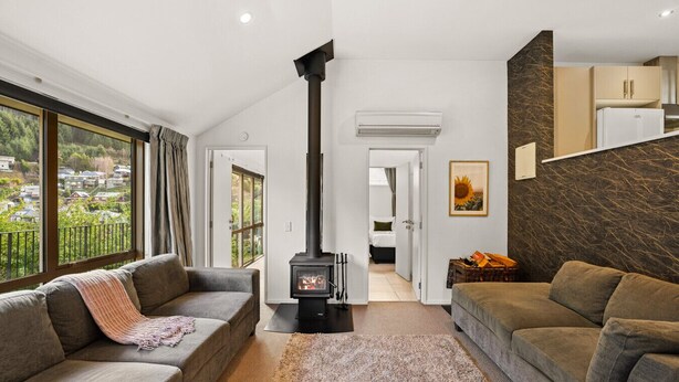 A modern living room with a fireplace, two sofas, a rug, and a view of the outside.