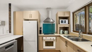 A compact kitchen with a refrigerator, microwave, stove, oven, and sink.