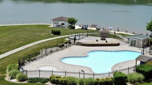 A swimming pool with a surrounding fence, a gazebo, and a small pavilion by the water.