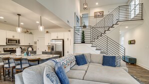 A modern kitchen with white cabinets, stainless steel appliances, and pendant lighting.