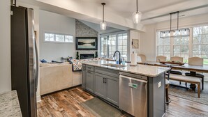 A modern kitchen with a built-in dishwasher, a large island with a sink, and a dining area with a table and chairs.