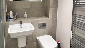A modern bathroom with a sink, toilet, and towel rack. - Double room in Luxury new flat. 1min to bus stop & grocery store! (Brentford)