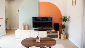 Una sala de estar moderna con un televisor de pantalla plana, una mesa de centro de madera y una planta grande.