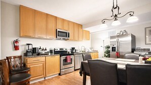 A modern kitchen with wooden cabinets, stainless steel appliances, and a dining area with a table and chairs.