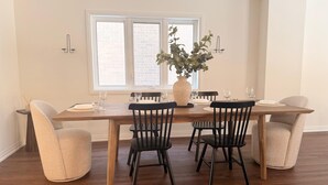 Un comedor con una mesa de madera, cuatro sillas y un jarrón con flores.