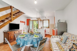 A dining area with a table set for two, a television, and a kitchen area with a refrigerator and a microwave. - La Casa Di Dadà, Oulx, Italy (Oulx)