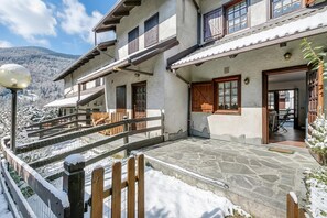 A two-story building with a stone facade, wooden balconies, and a snow-covered landscape. - La Casa Di Dadà with Terrace and Garden, Oulx, Italy (Oulx)