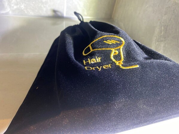 A black drawstring bag with a golden embroidered design and the text "Hair Dryer".