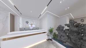 A modern reception area with a marble reception desk, a computer, and a potted plant. - Zhihui Star Business Hotel (Chantrea)